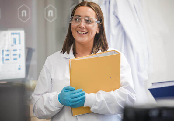 Laboratory professional holding documents in a research environment.